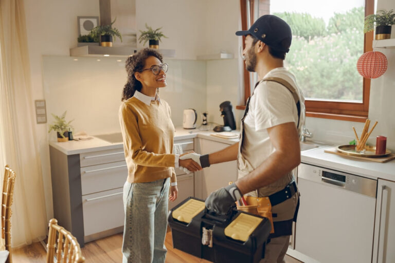 Réparateur professionnel en uniforme serrant la main d'une femme alors qu'il se tenait à la maison